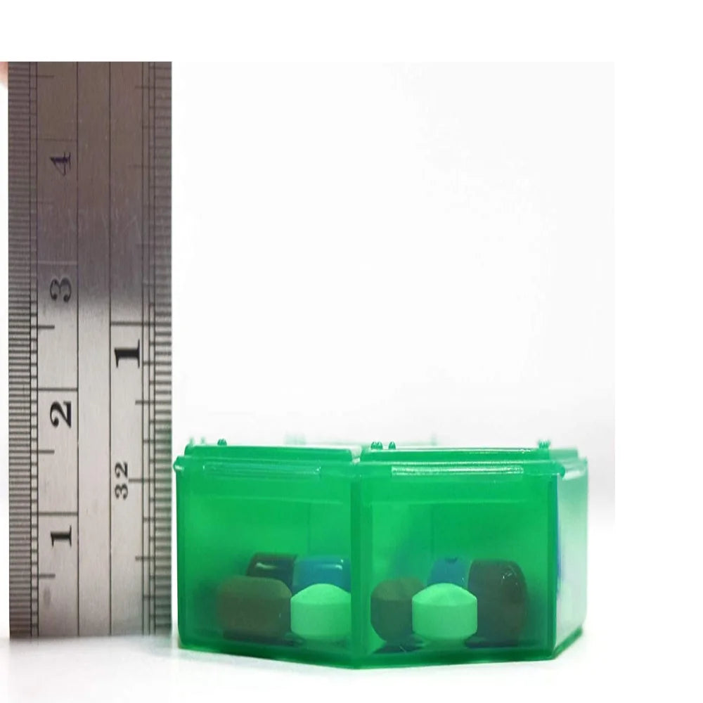 Green pill organizer with compartments next to a ruler on a white background
