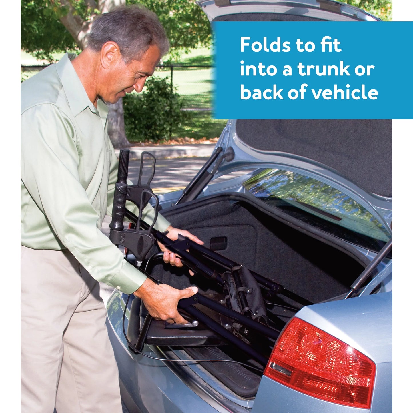 Man loading a folded car seat into a vehicle's trunk with text 'Folds to fit into a trunk or back of vehicle'.