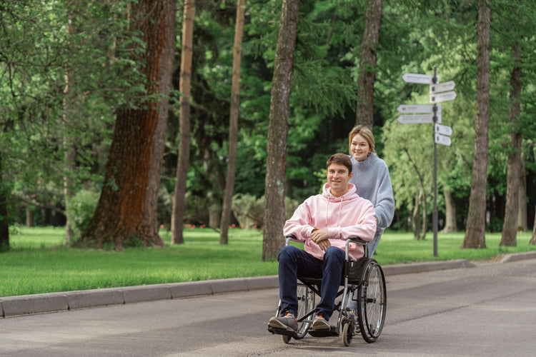 Person in wheelchair enjoying a walk in the park with companion — mobility and comfort in motion.