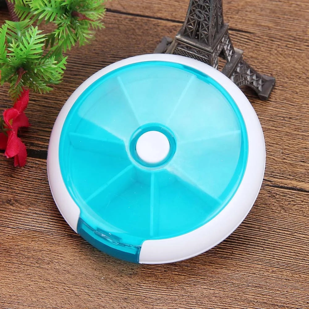 Blue and white round pill organizer on a wooden surface with decorative items.