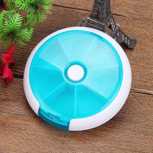 Blue and white round pill organizer on a wooden surface with decorative items.
