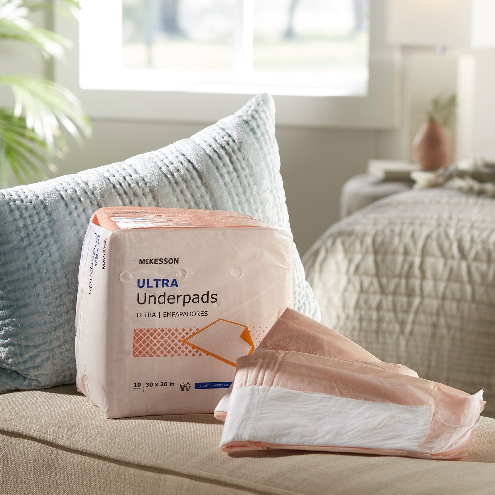 Package of McKesson Ultra Underpads on a couch with a blurred background