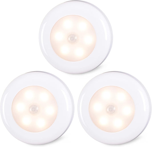 Three white round night lights with a warm glow on a white background

