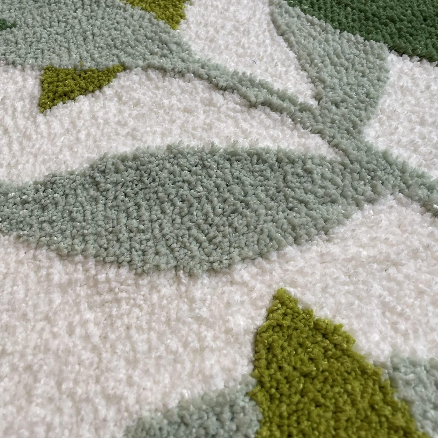 Close-up of a textured rug with green, gray, and white patterns

