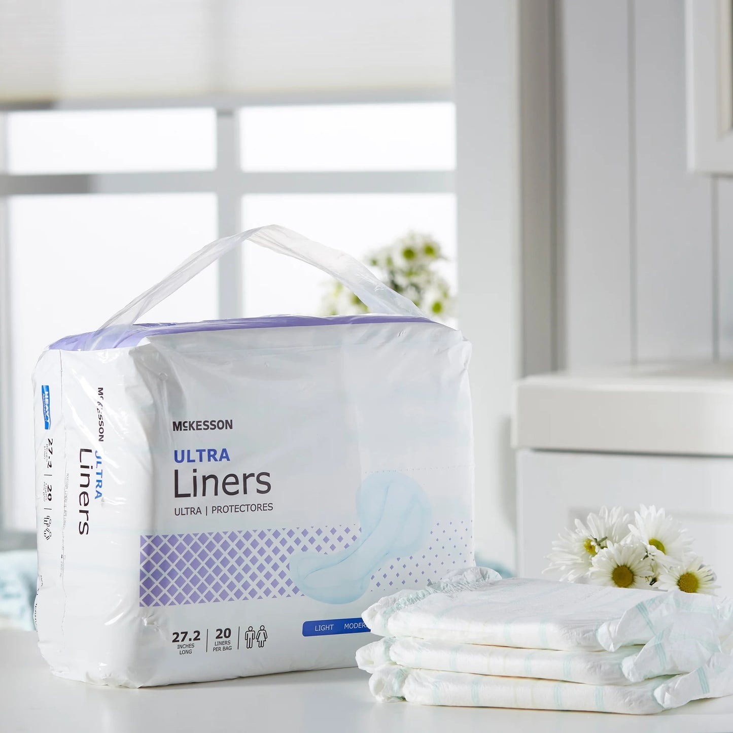 Package of McKesson Ultra Liners on a white surface with flowers in the background
