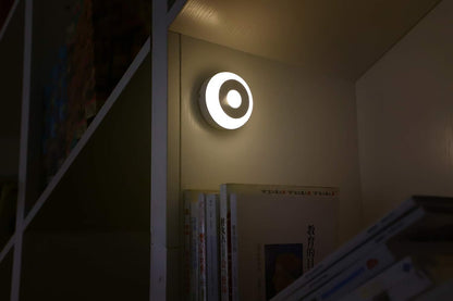 Round wall light fixture on a wall in a dimly lit room.

