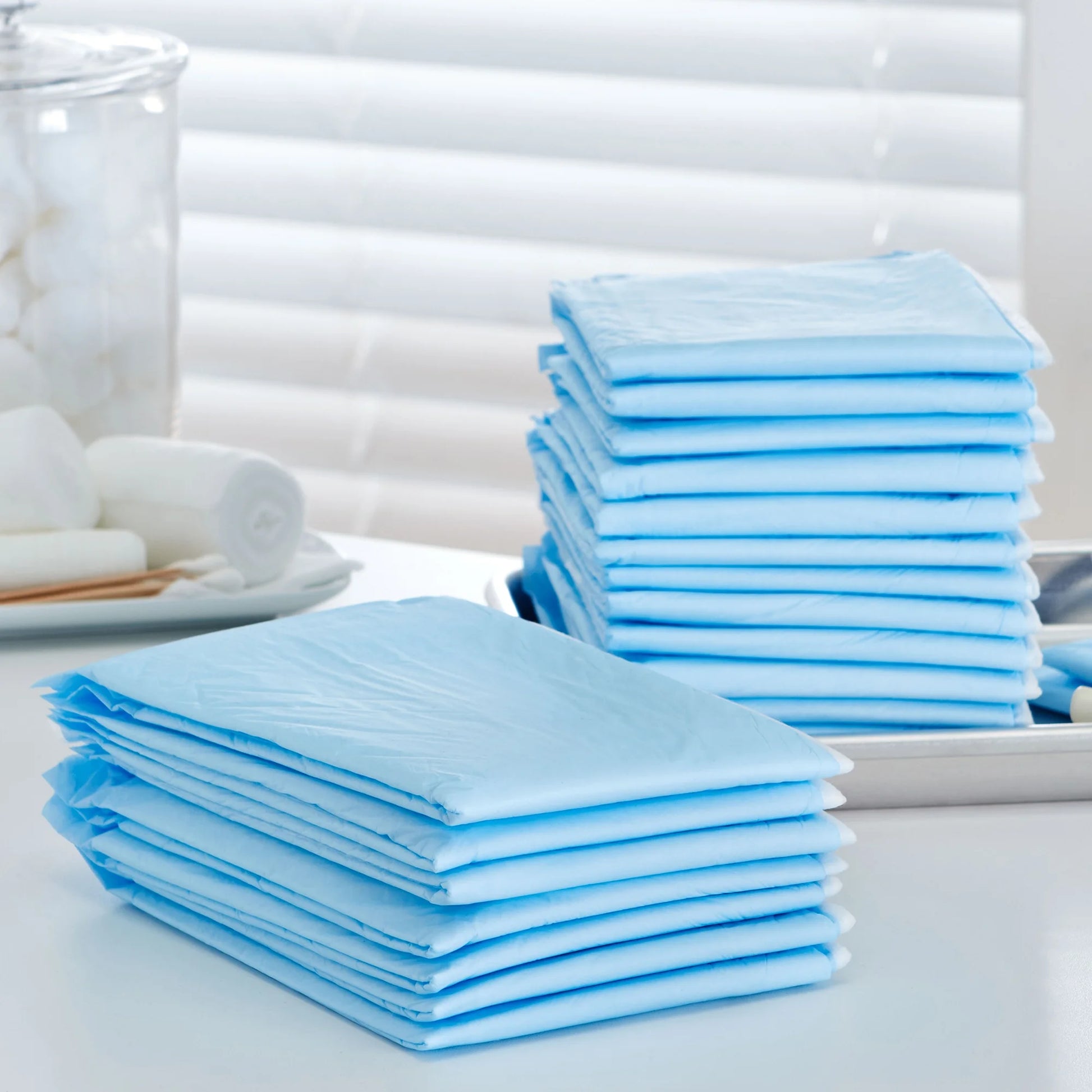 Stacks of blue disposable diapers on a white surface with a blurred background