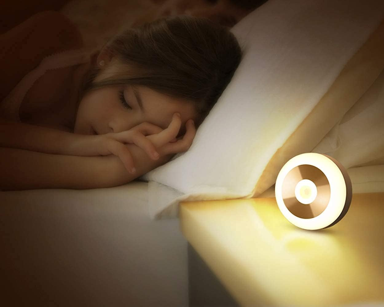 Woman lying in bed with a round night light emitting a warm glow.

