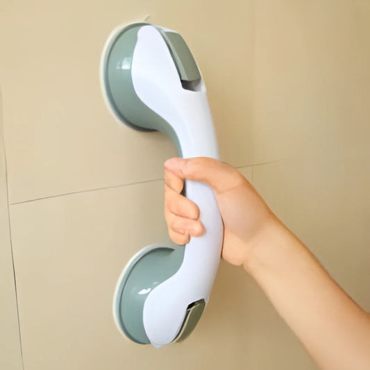 Hand holding a white and green grab bar against a beige tiled wall.

