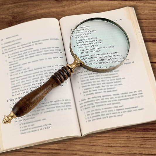 Magnifying glass over an open book on a wooden surface