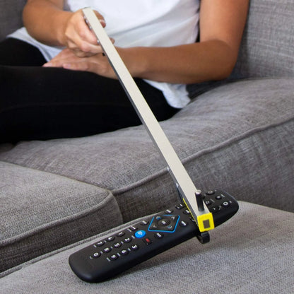 Person using a remote control holder on a gray couch