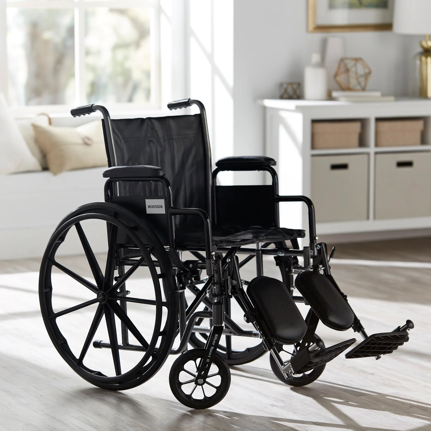 Black wheelchair in a room with a couch and shelves.

