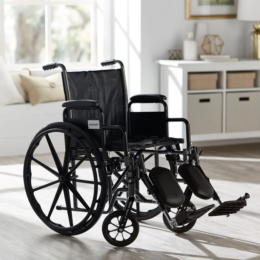 Black wheelchair in a room with a couch and shelves.

