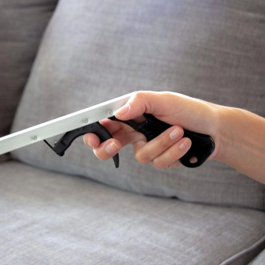 Hand holding a metal tool against a gray couch