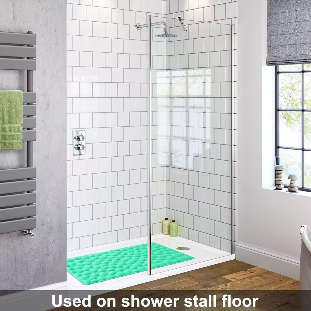 Shower stall with a green textured mat on the floor, white tiled walls, and a window.