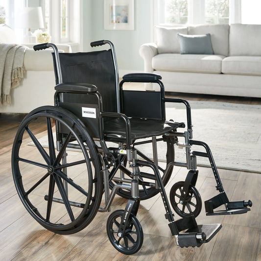 Wheelchair in a living room setting with a couch and windows in the background.


