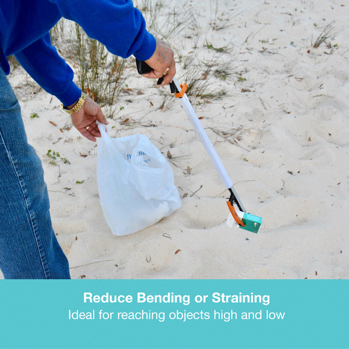 Person in blue sweatshirt and jeans using a reaching tool to pick up trash on the beach.