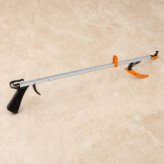 A long-handled claw tool with a silver metal shaft, black textured handle, and bright orange spring-loaded tips, shown on a beige stone tile background.