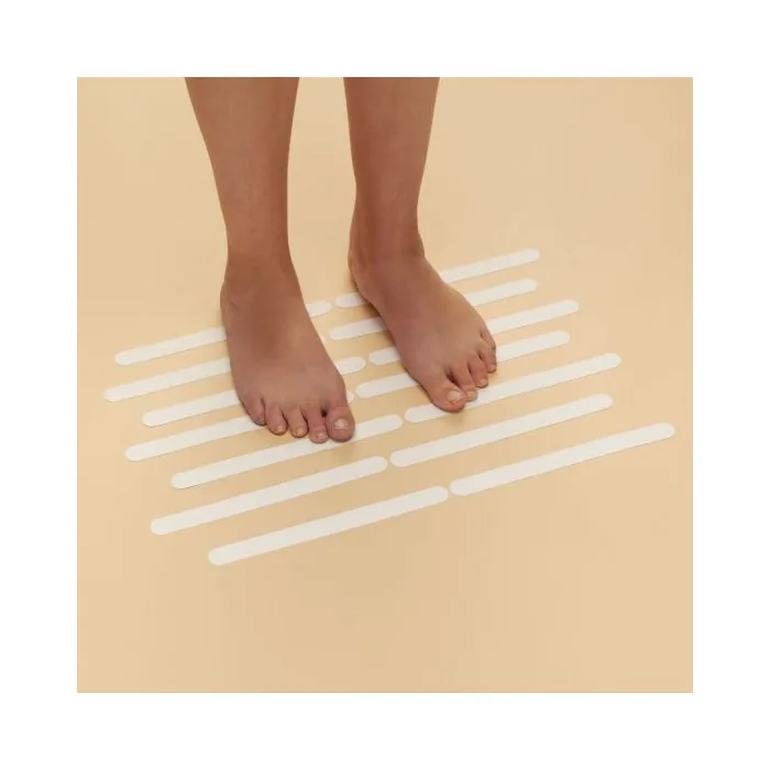 Feet standing on a beige surface with white adhesive strips.