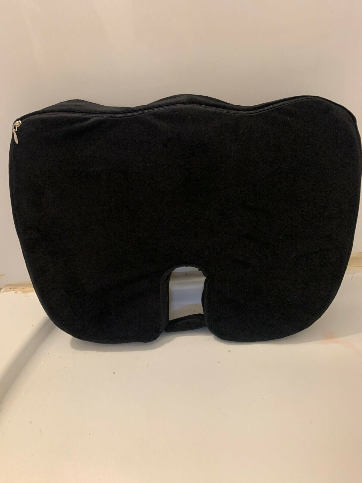 Black U-shaped travel pillow on a white surface with a light gray background

