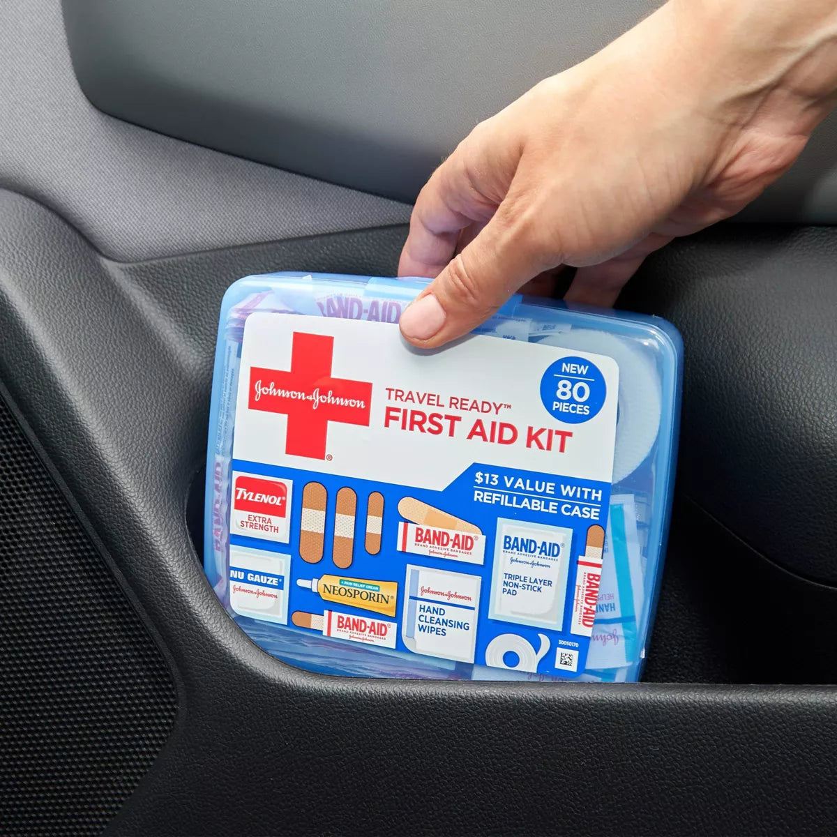 Johnson & Johnson travel first aid kit held by a hand inside a car.

