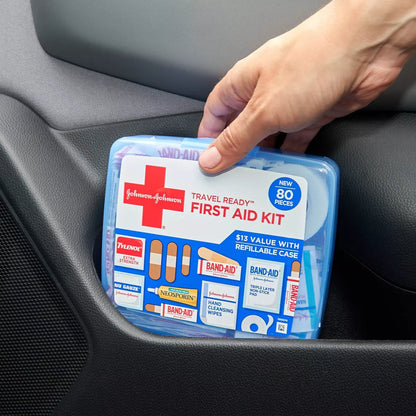 Johnson & Johnson travel first aid kit held by a hand inside a car.

