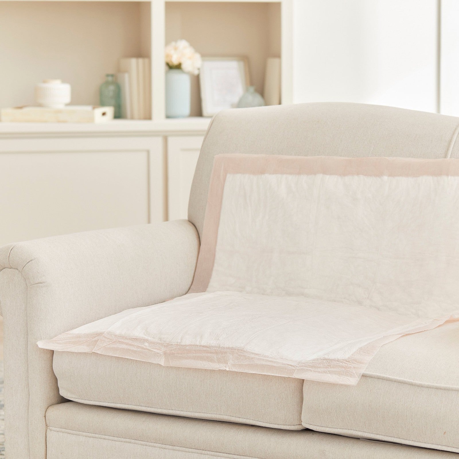 Beige sofa with a protective cover on a neutral background