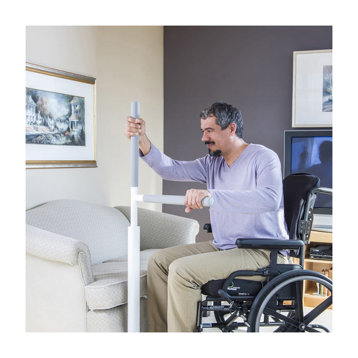 Man in a wheelchair gripping the floor rail in a living room setting.