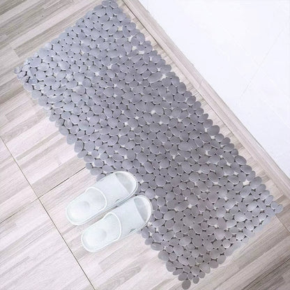 Gray textured bath mat on a wooden floor with white slippers.