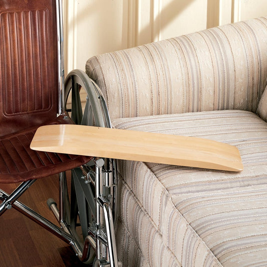 Wooden transfer board on a striped sofa next to a wheelchair

