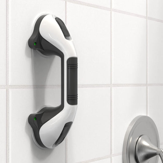 White and black grab bar mounted on a tiled bathroom wall.