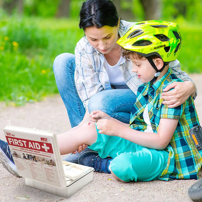 Woman and child with a helmet reading a first aid book outdoors

