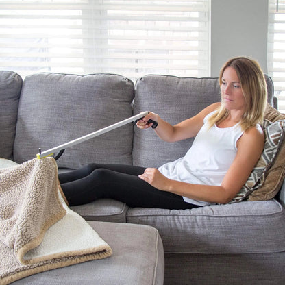 Woman sitting on a couch using a reacher