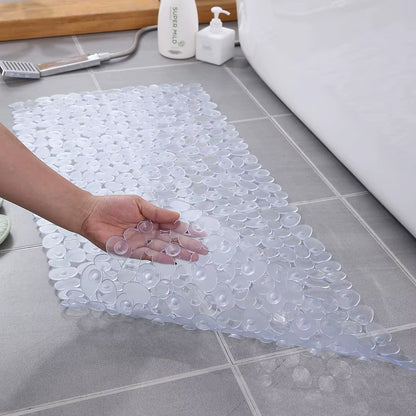 Clear bath mat with textured surface on a bathroom floor, hand holding a small clear object.